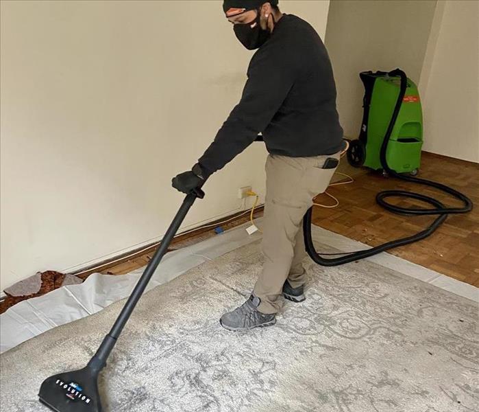 A SERVPRO Employee is extracting water from a carpet.