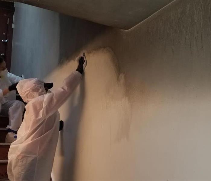 A SERVPRO employee is cleaning soot from a wall.