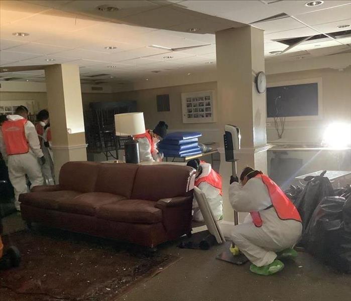 SERVPRO employees cleaning a basement after damage.