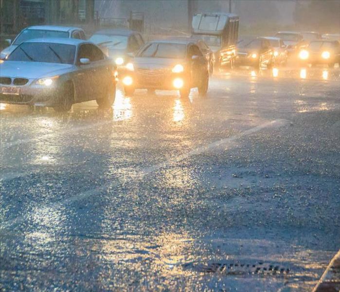 Cars driving on a busy road in heavy rain.